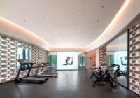 Een persoon vervangt het loopvlak van een opvouwbare loopband voor optimale prestaties in de fitnessruimte.
